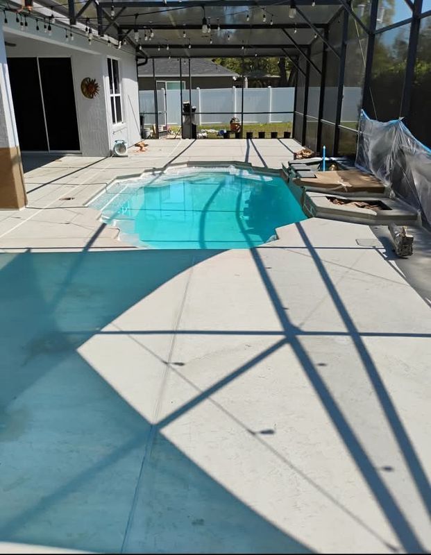 Covered backyard pool beside a patio with lounge chairs and a screened enclosure.