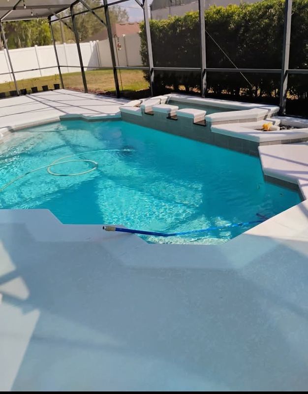 Backyard swimming pool with turquoise water, white lounge chairs, and a screened patio.