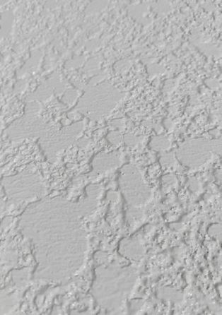 Close-up of a light gray textured wall with rough plaster-like surface.