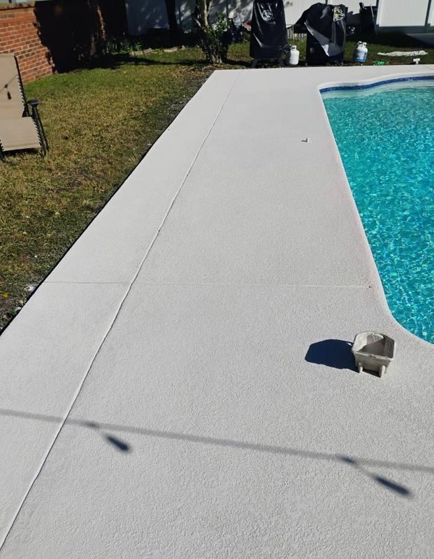 Poolside concrete deck beside blue water, with a small object on the ground and yard chairs in the background.