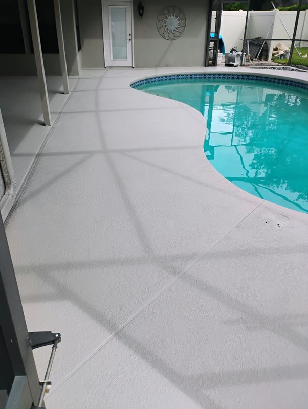 Patio beside a turquoise swimming pool with a light gray concrete deck and screened enclosure.