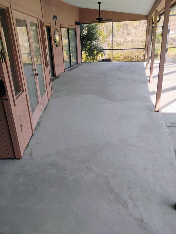 Covered porch with concrete floor, pink doors, ceiling fans, and a screened view of trees beyond.