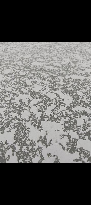Gray-and-white speckled surface with a scattered, pebble-like pattern