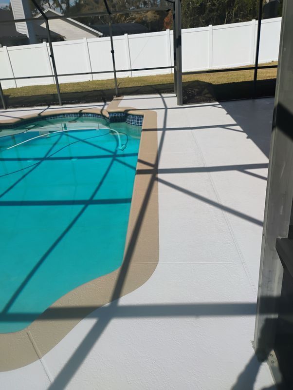 Sunlit backyard pool deck with turquoise pool water and white patio beside a glass fence.