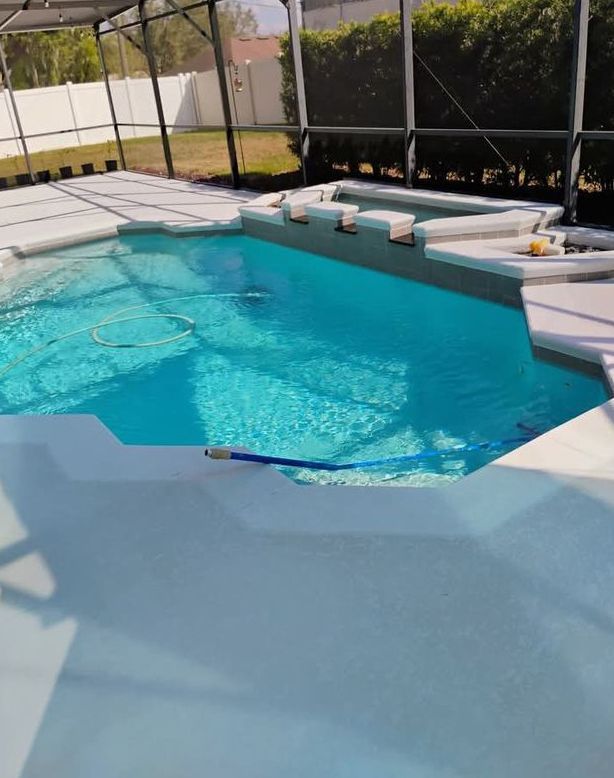Outdoor swimming pool with turquoise water, white lounge chairs, and a shaded patio area.