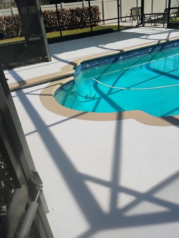 Swimming pool with turquoise water, tan deck, and metal railings in bright sunlight.