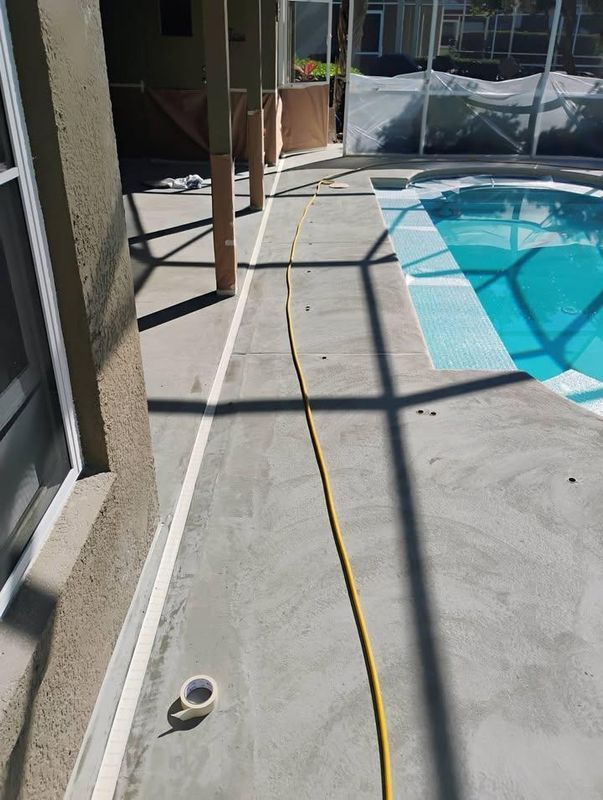 Poolside concrete patio with a yellow hose and a small white cup near the edge of the pool.