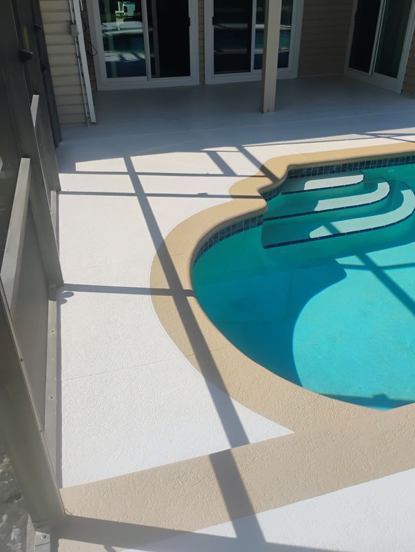 Back patio with white tile deck beside a turquoise swimming pool and shadowed glass doors.
