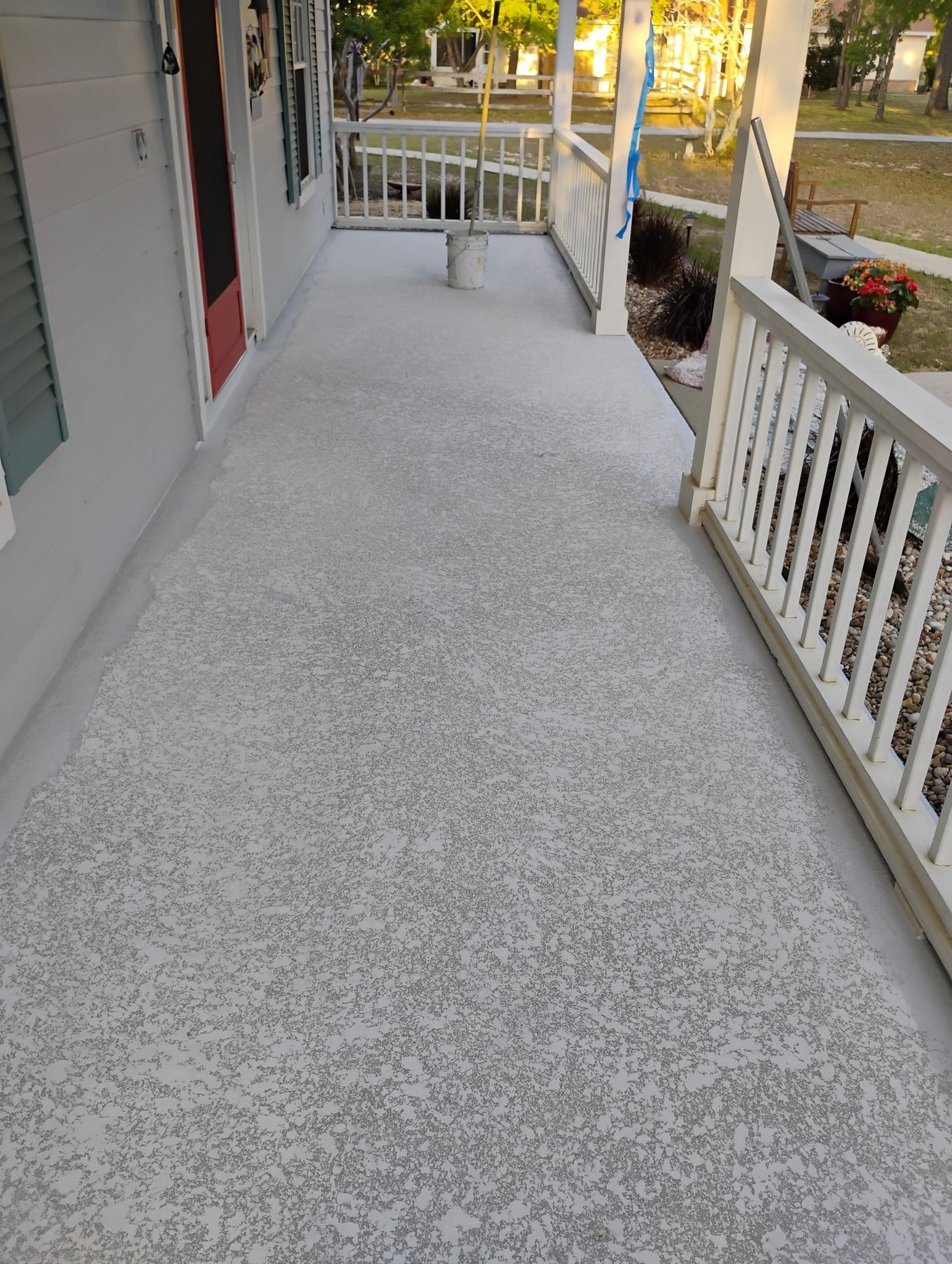 White carpeted porch with white railings and steps outside a house.