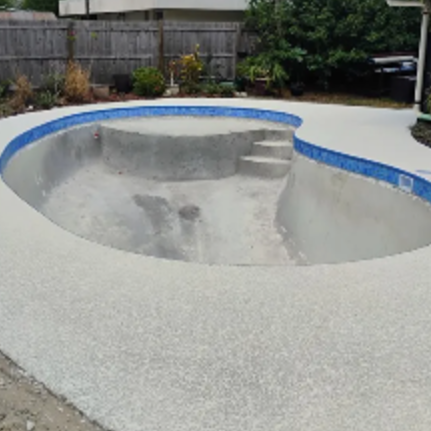 Empty concrete swimming pool with blue coping in a backyard.