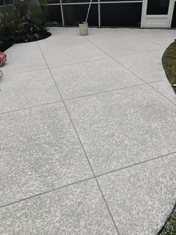 Curved light-gray concrete patio with square tiles beside a lawn and house windows.