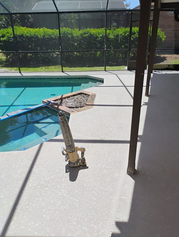 Swimming pool edge with a pool vacuum cleaner on the deck under a shaded patio.