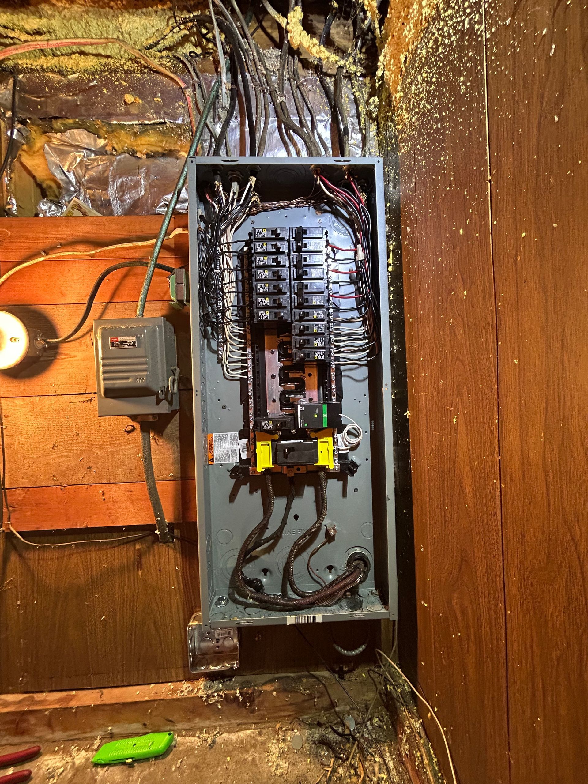 An electrical box is hanging on a wooden wall.