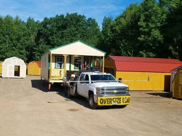 A white truck hauling a small building labeled 