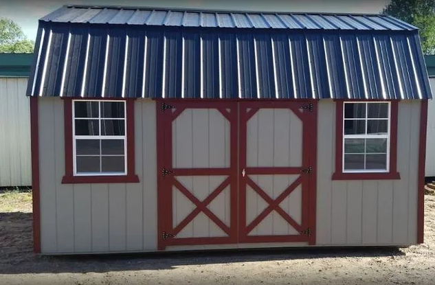 Tan shed with red trim, double doors, two windows, and a black metal roof.