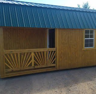 Wooden cabin with green metal roof and small porch.