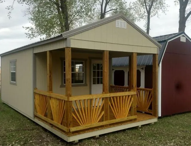 Tan shed with a wooden porch and a red shed next to it in a grassy area.