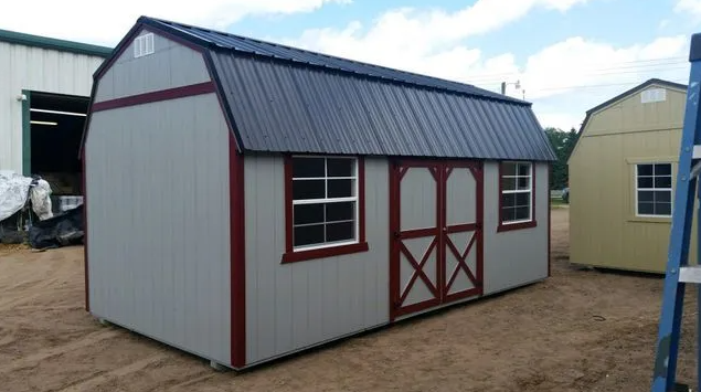Gray shed with red trim, blue roof, two windows, and double doors.