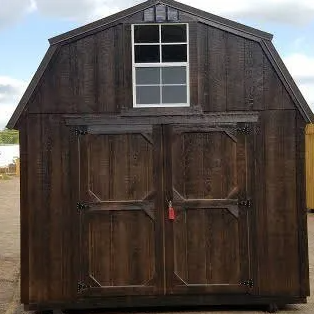 Dark brown barn-style shed with double doors and a small window on a sunny day.