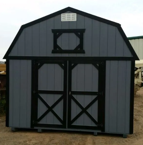Gray and black barn-style shed with double doors and small window under the roof peak.