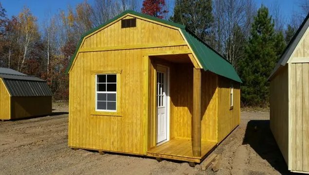 Yellow wooden shed with green roof and small porch.