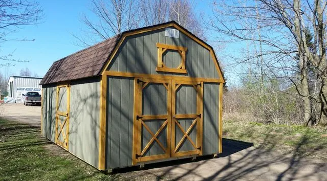 Green and brown barn-style shed with a brown roof, set outside on a sunny day.