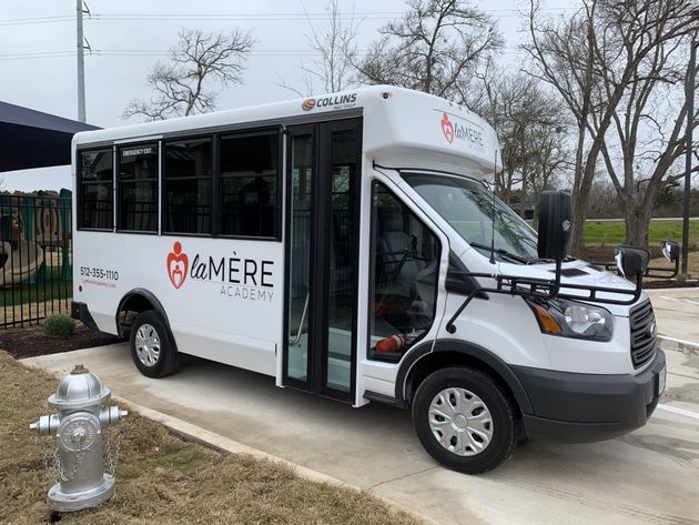 White shuttle van with wheelchair ramp parked on a sidewalk outside a building