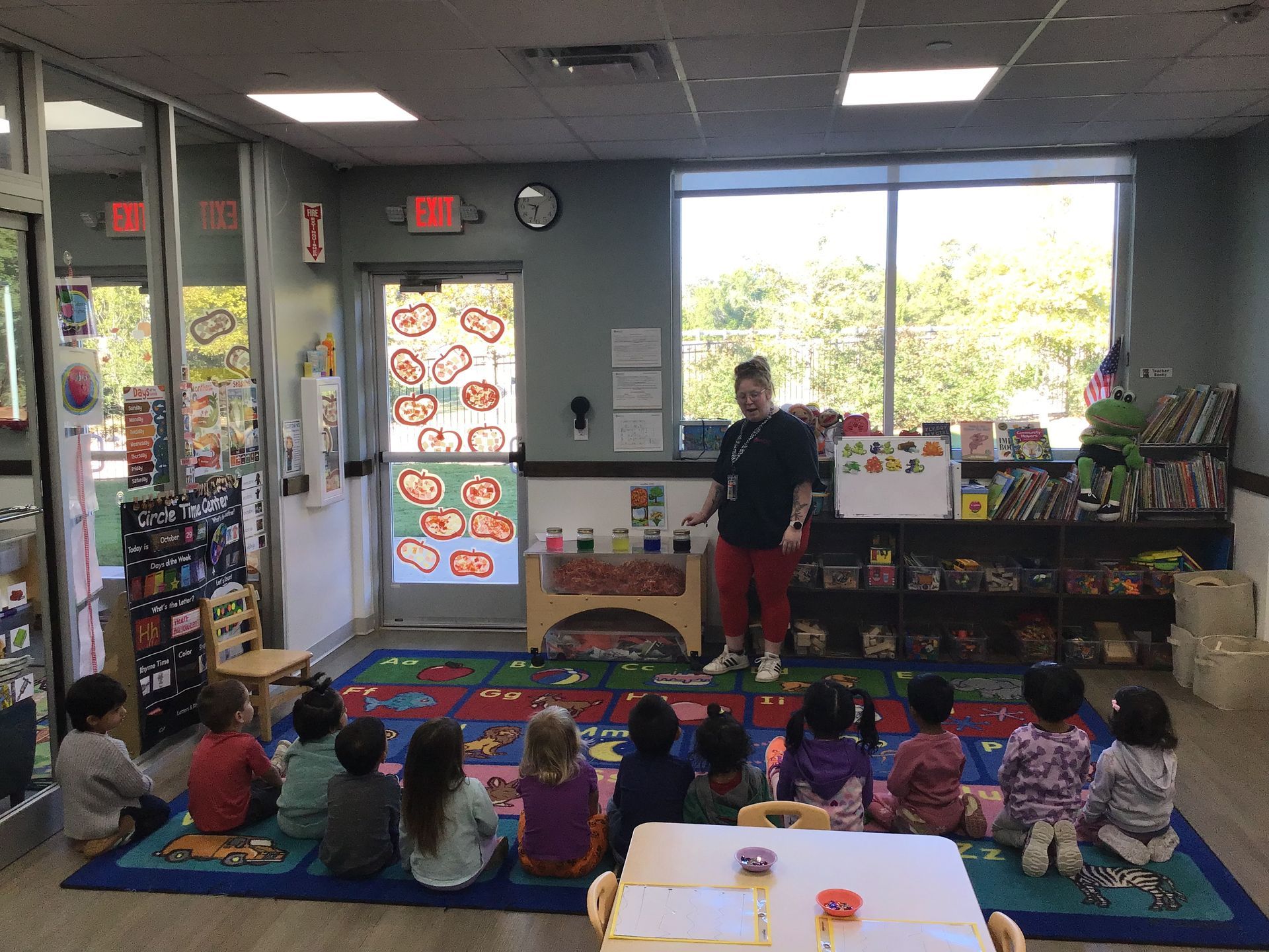 Teacher speaking to seated children during story time in a colorful classroom