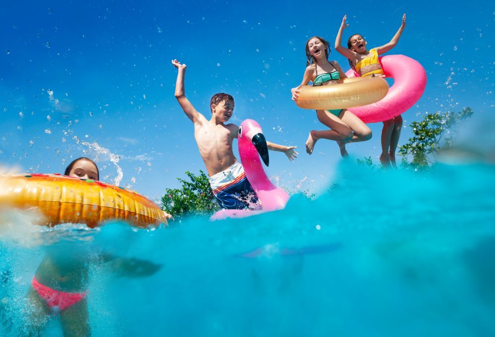 People splashing in bright inflatable tubes on a sunny blue pool or water park day