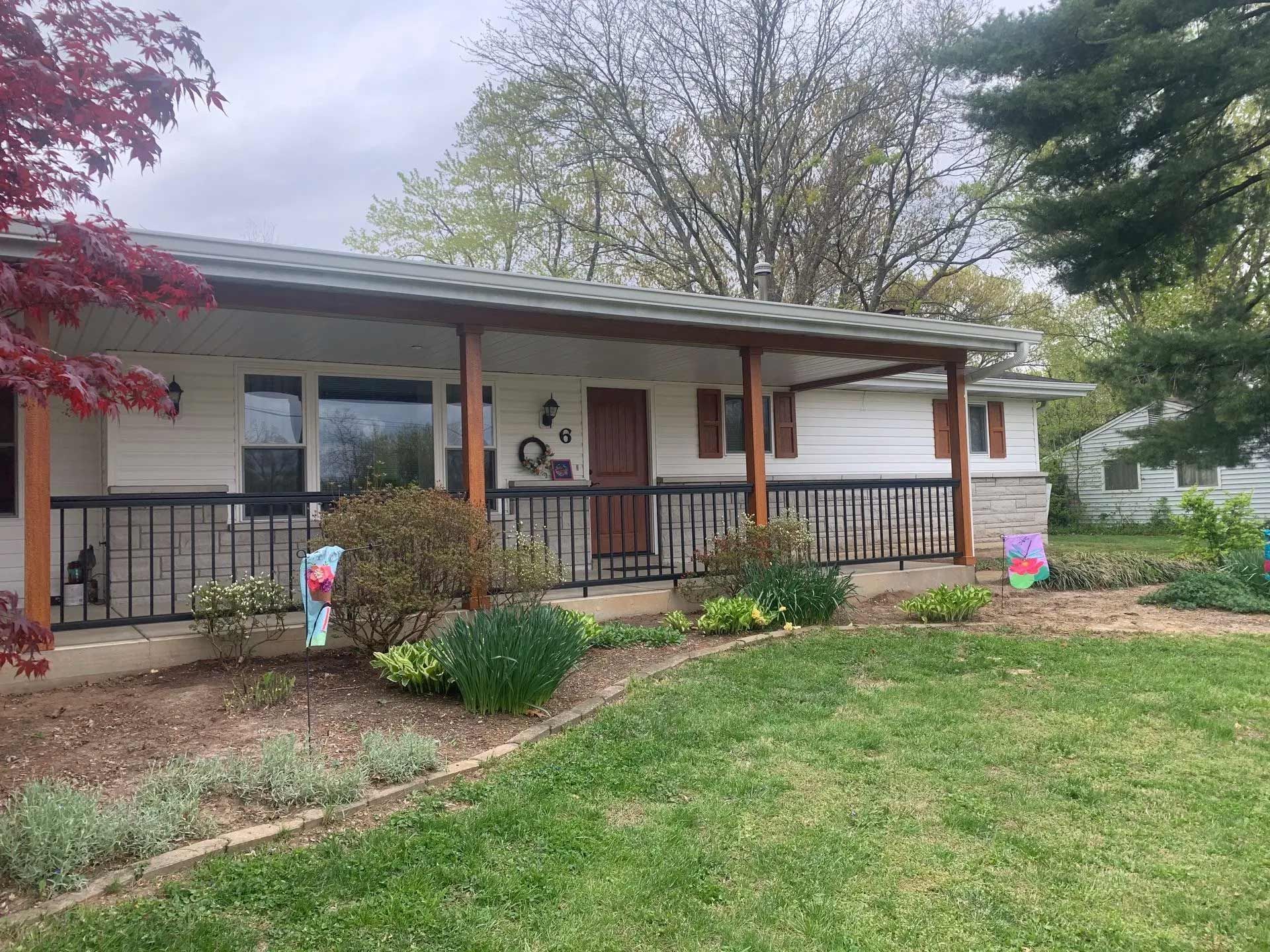 A house with a porch and a large lawn in front of it.