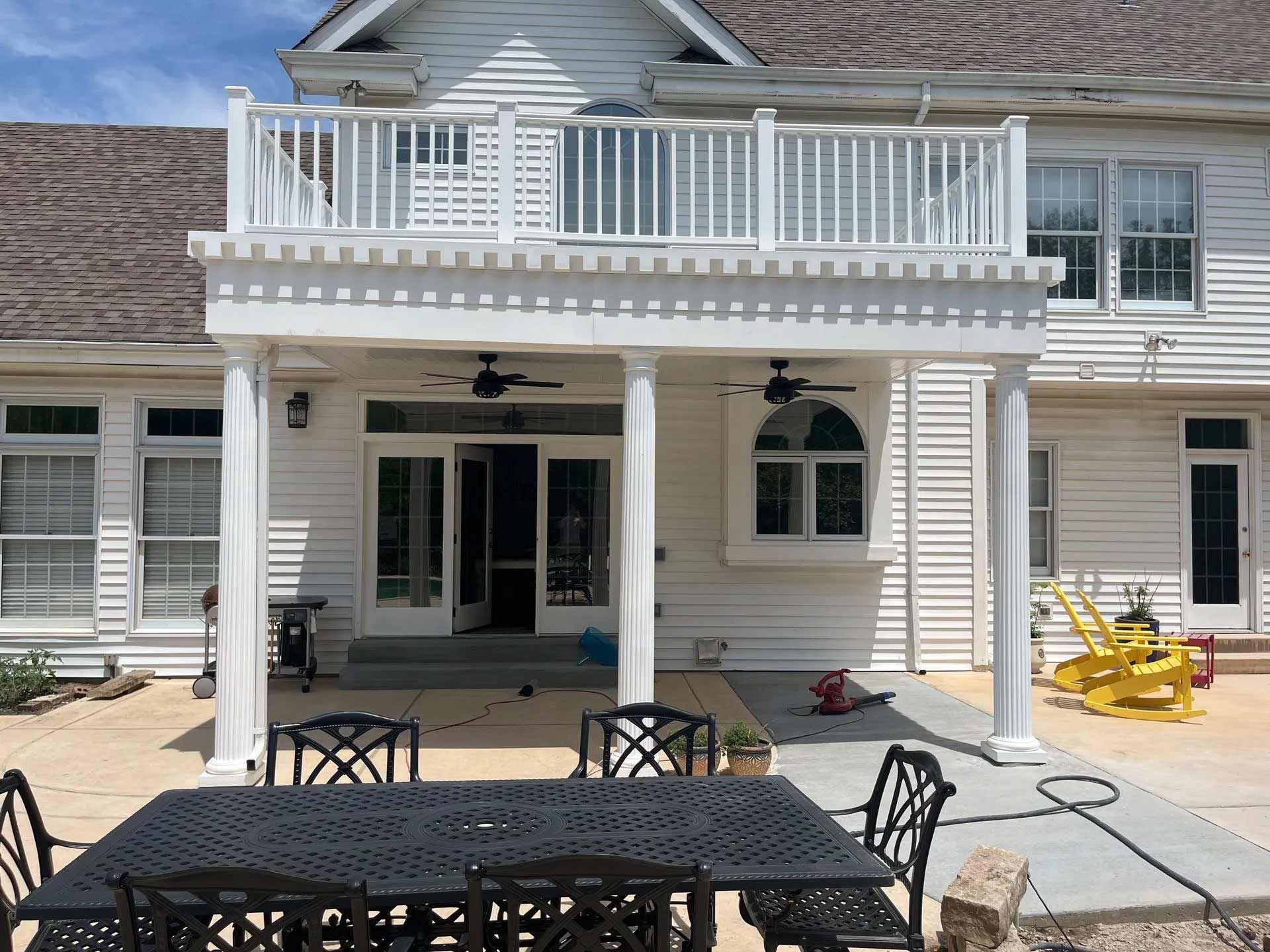 A large white house with a patio area with a table and chairs