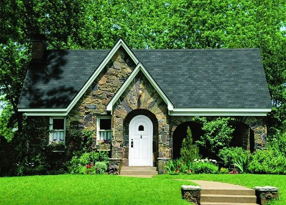 A stone house with a black roof and a white door