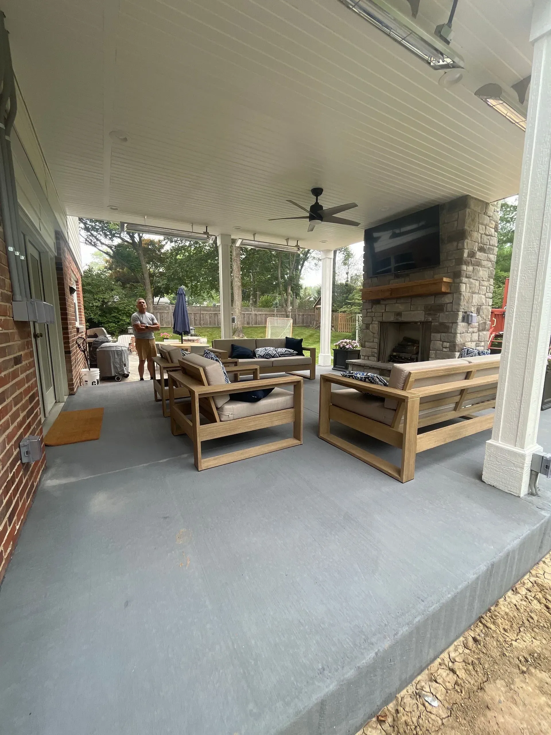 A covered patio with furniture and a fireplace.