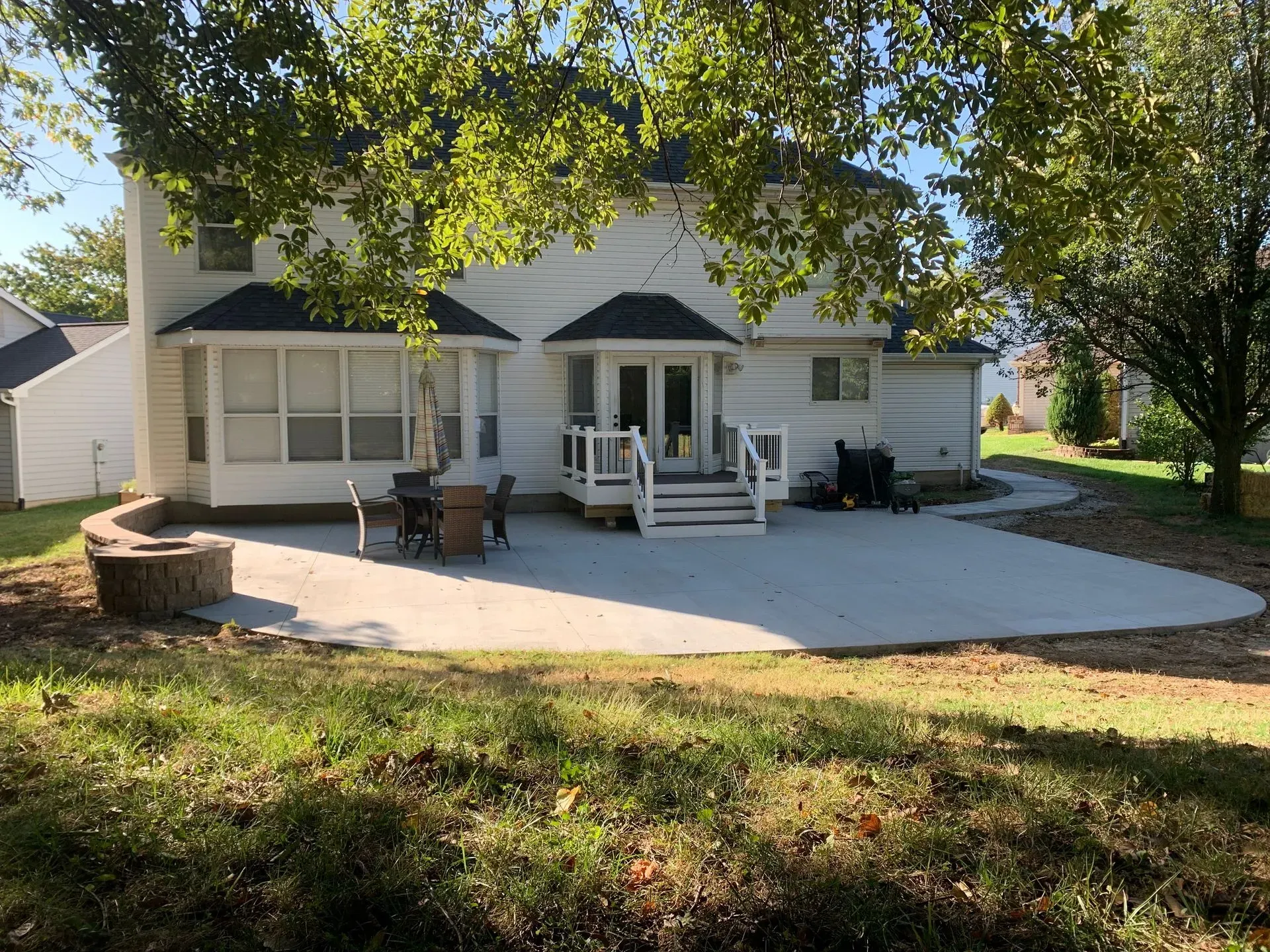 A large white house with a patio and a fire pit in front of it.