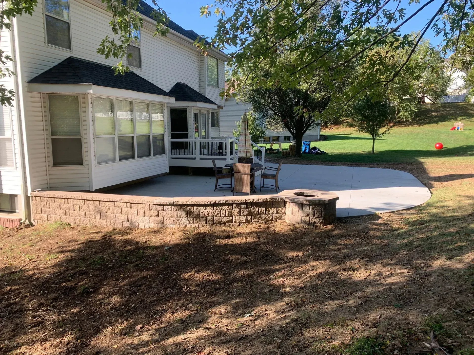 A white house with a patio and a fire pit in front of it.