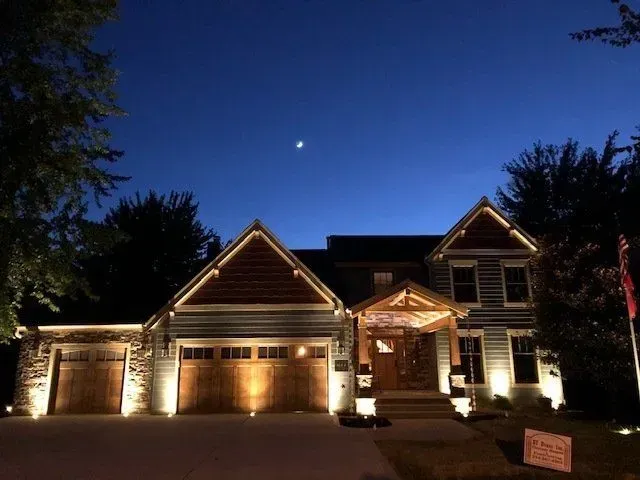 A large house is lit up at night with the moon in the sky