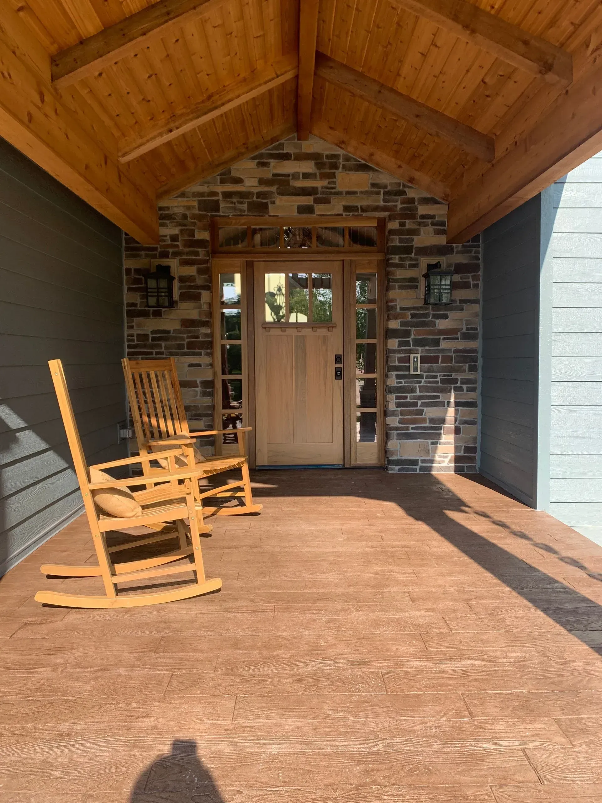 There are two rocking chairs on the porch of a house.