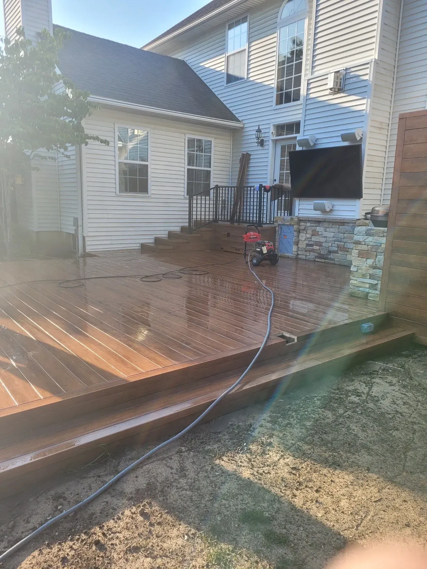 A person is cleaning a deck with a hose in front of a house.