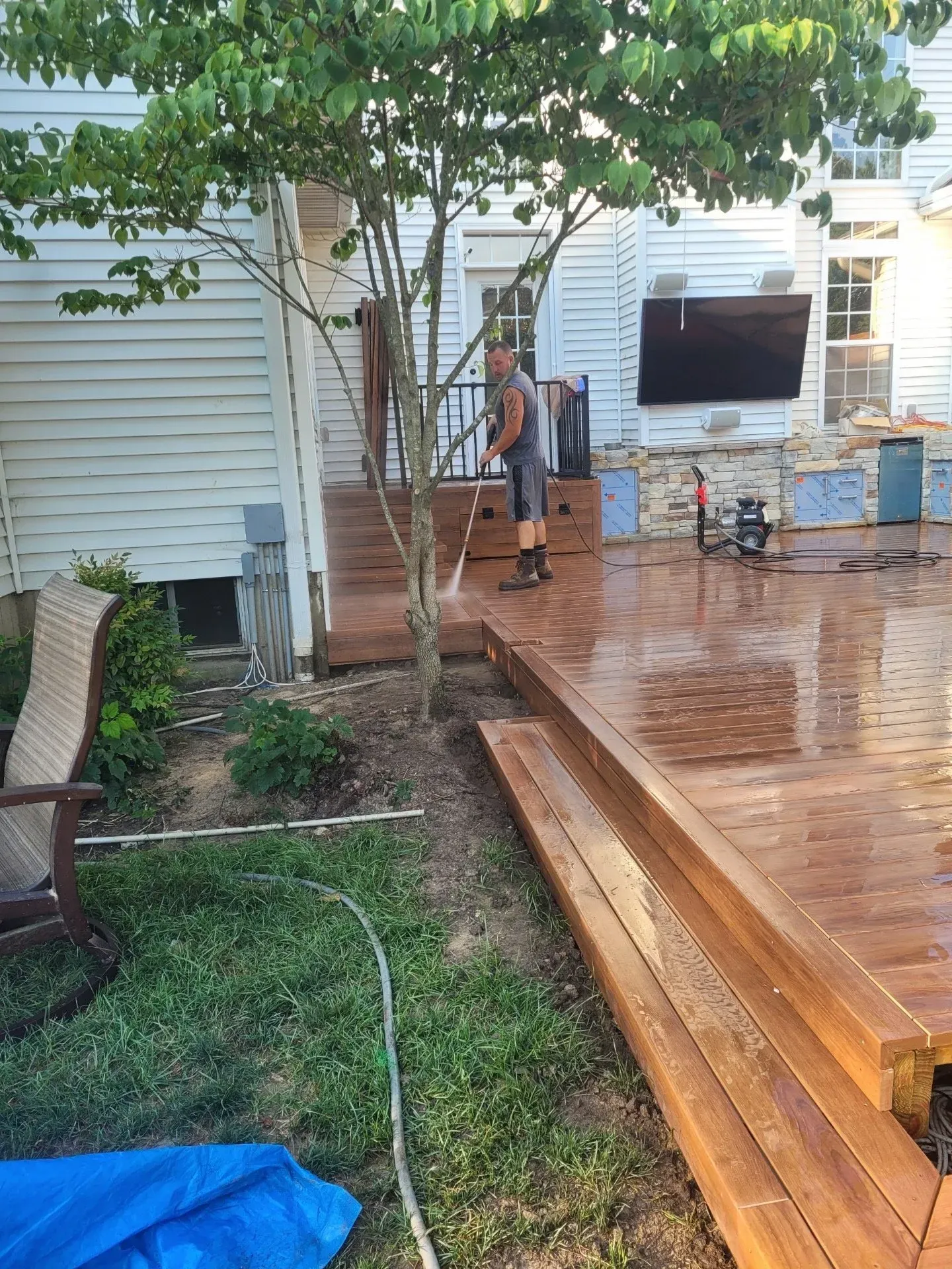 A man is cleaning a wooden deck with a pressure washer.