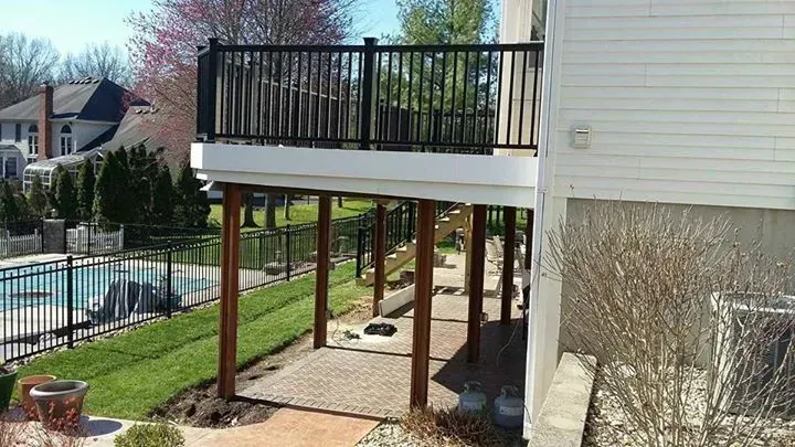 A white house with a large deck and a pool in the backyard.
