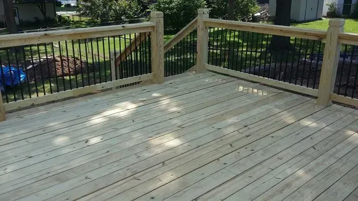 A wooden deck with a metal railing and stairs.
