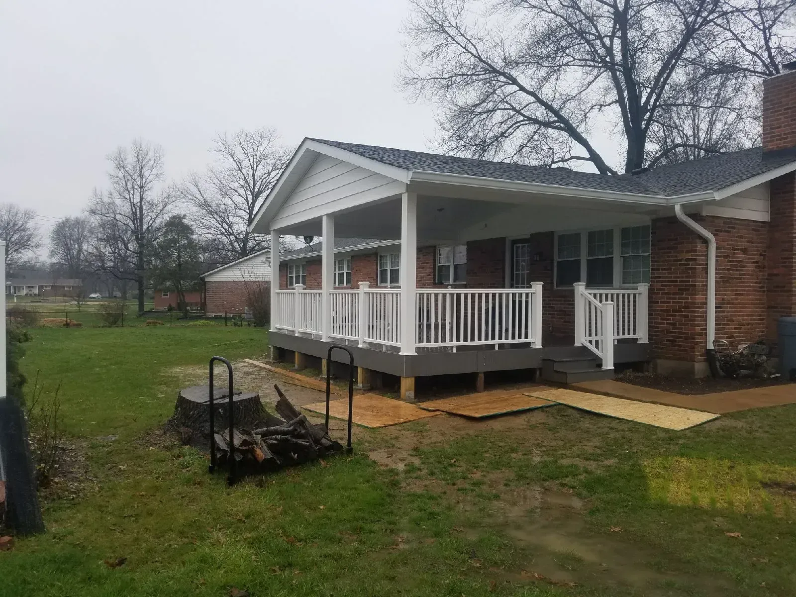 A house with a porch and a fire pit in front of it.