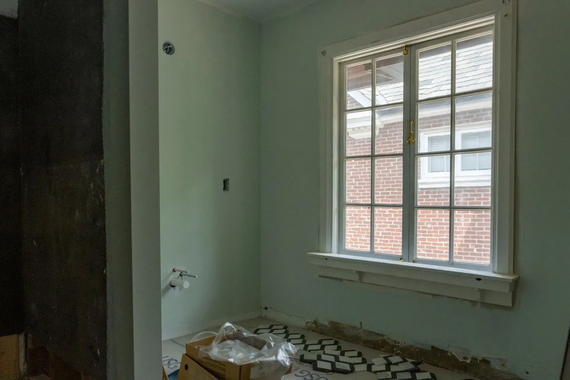 An empty room with a window and a brick wall.