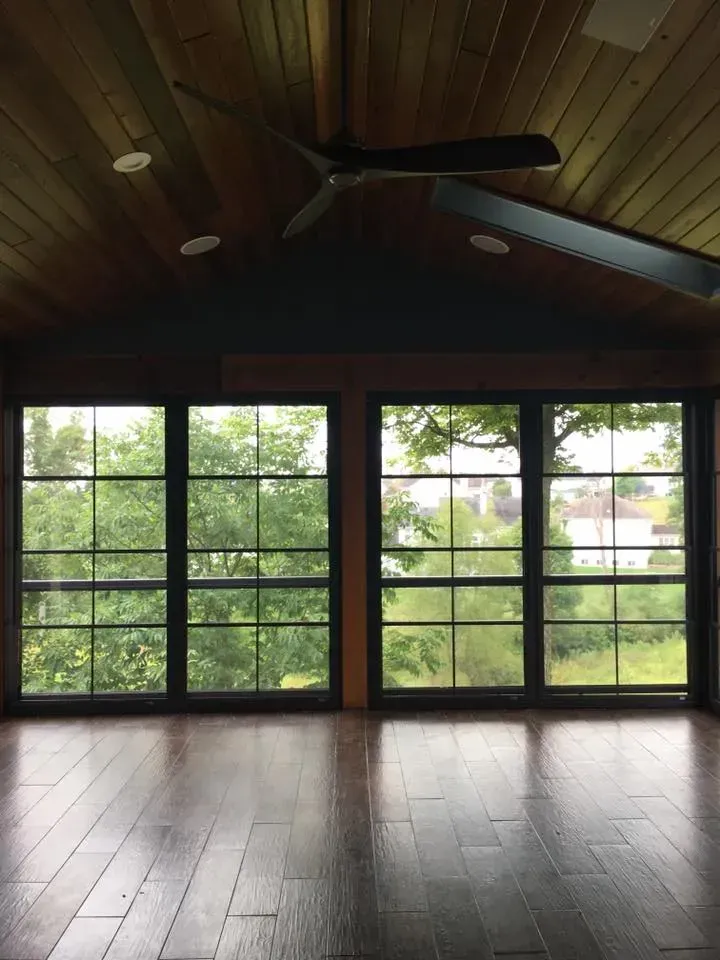 An empty room with a lot of windows and a ceiling fan.