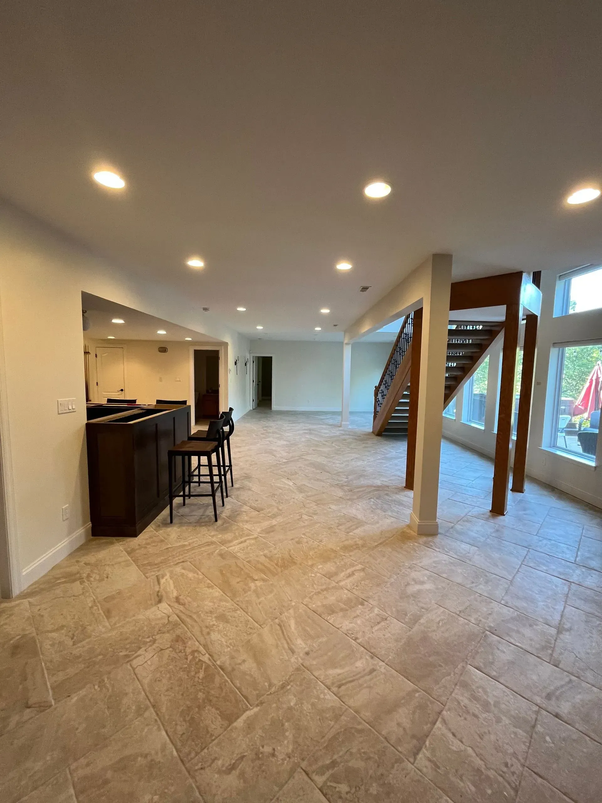 A large empty room with a staircase and a bar.
