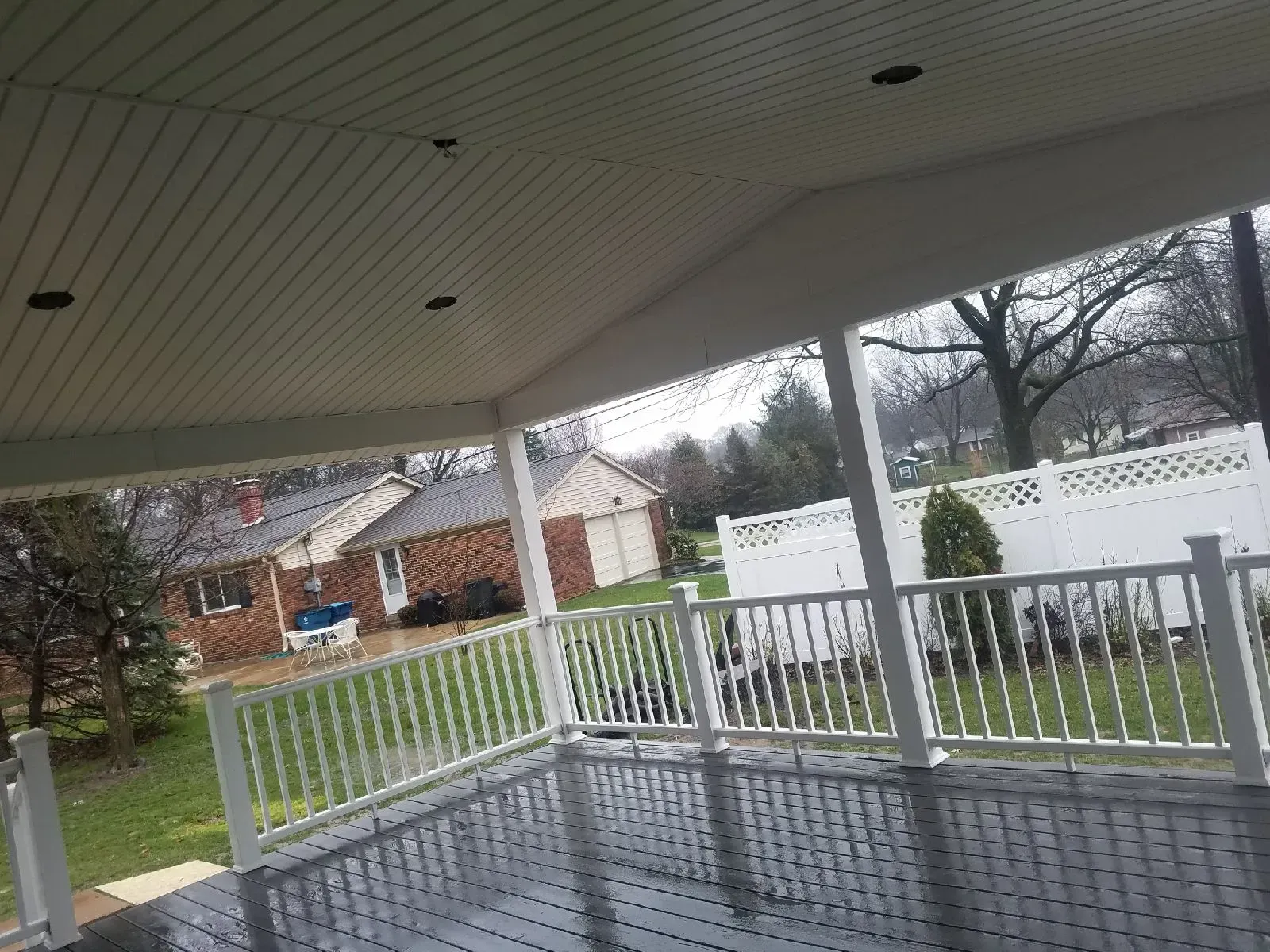 A porch with a white railing and a brick house in the background