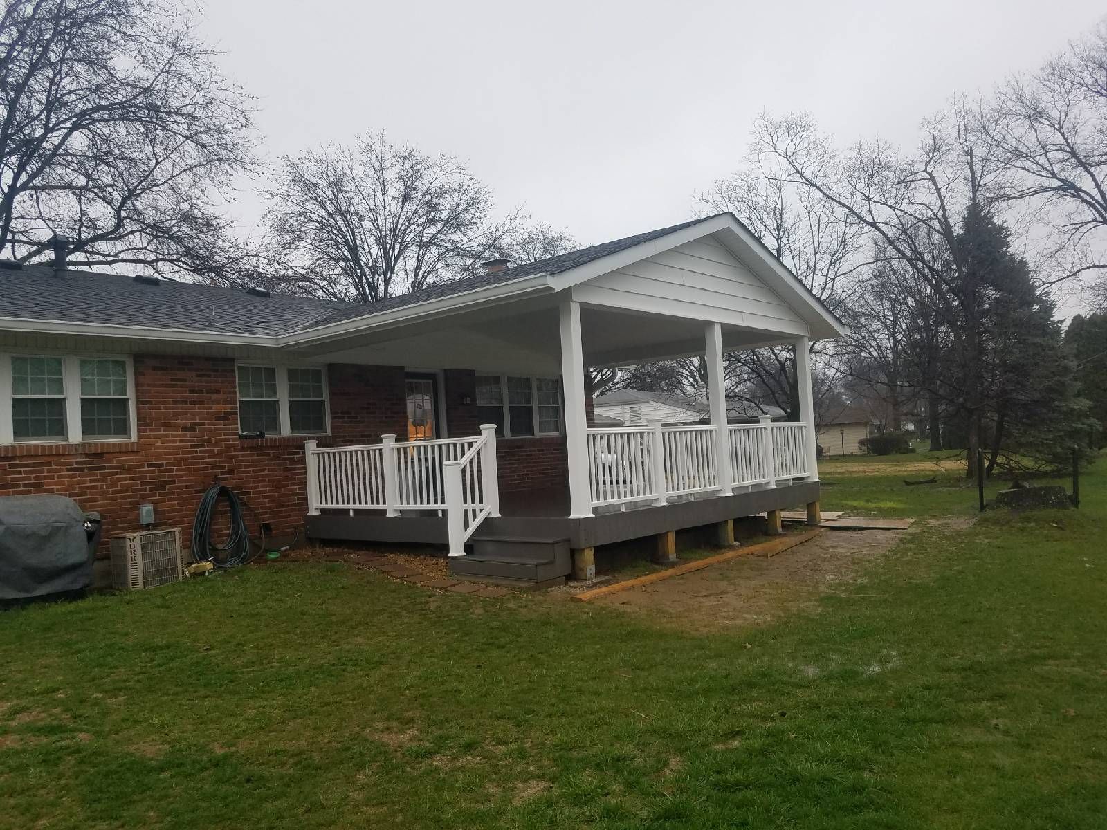 A brick house with a porch and a white railing.