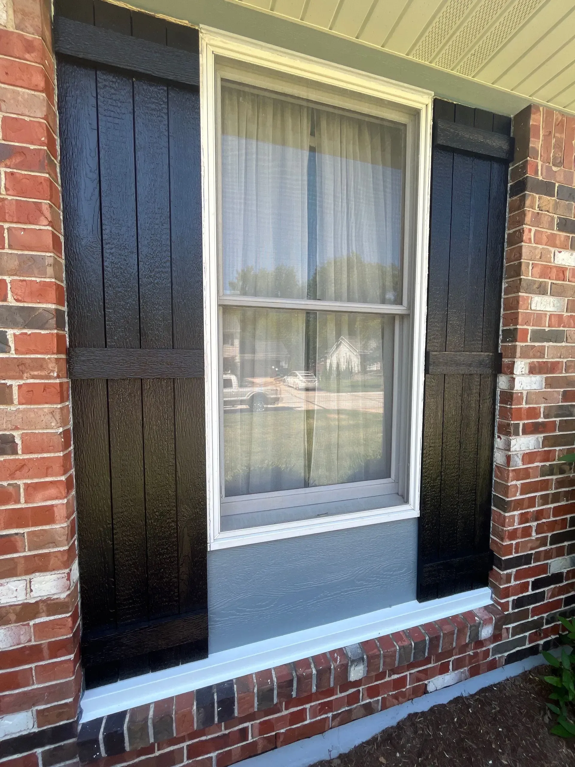 A brick house with black shutters on the windows