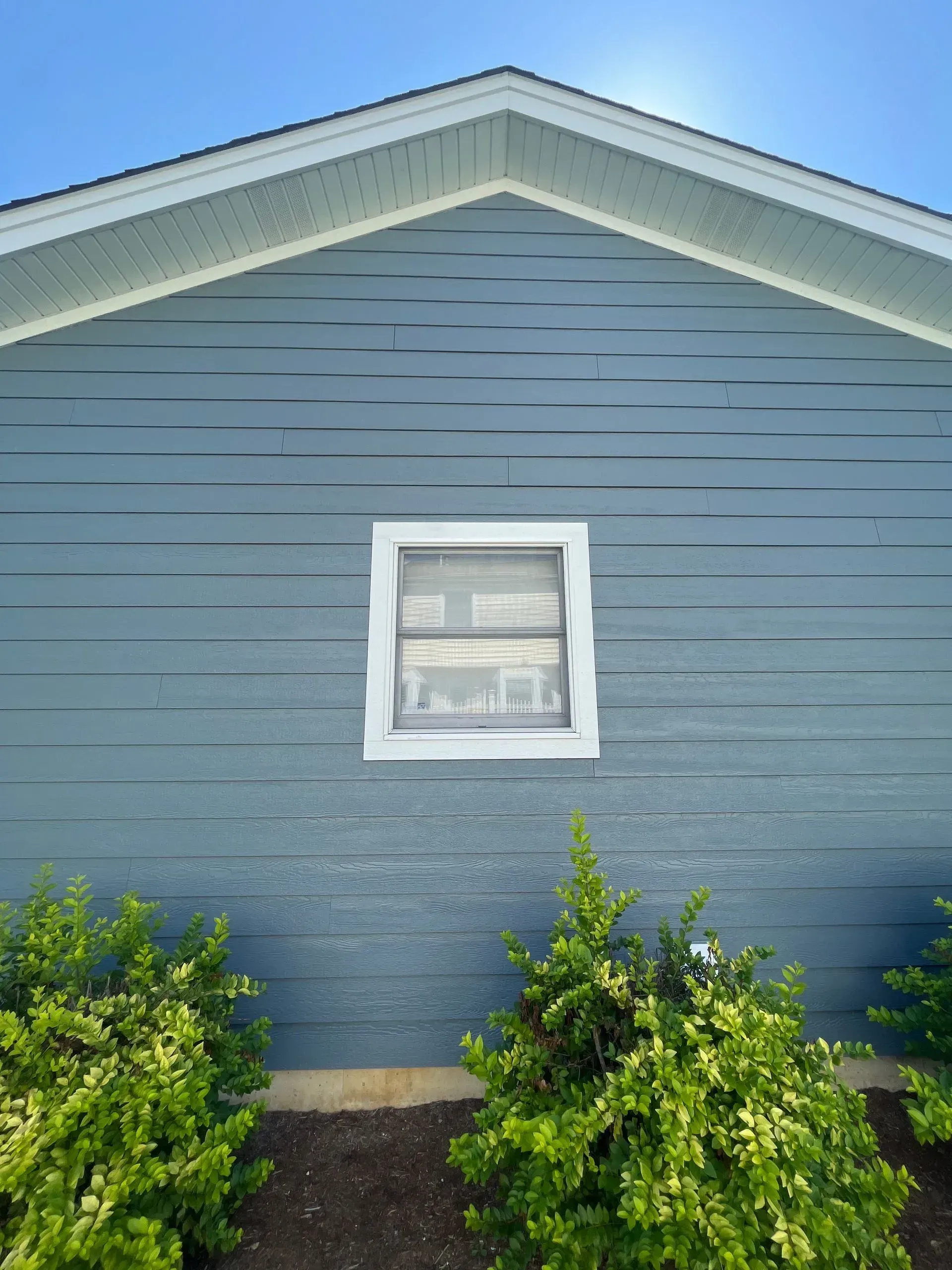 A blue house with a white window and a blue sky in the background