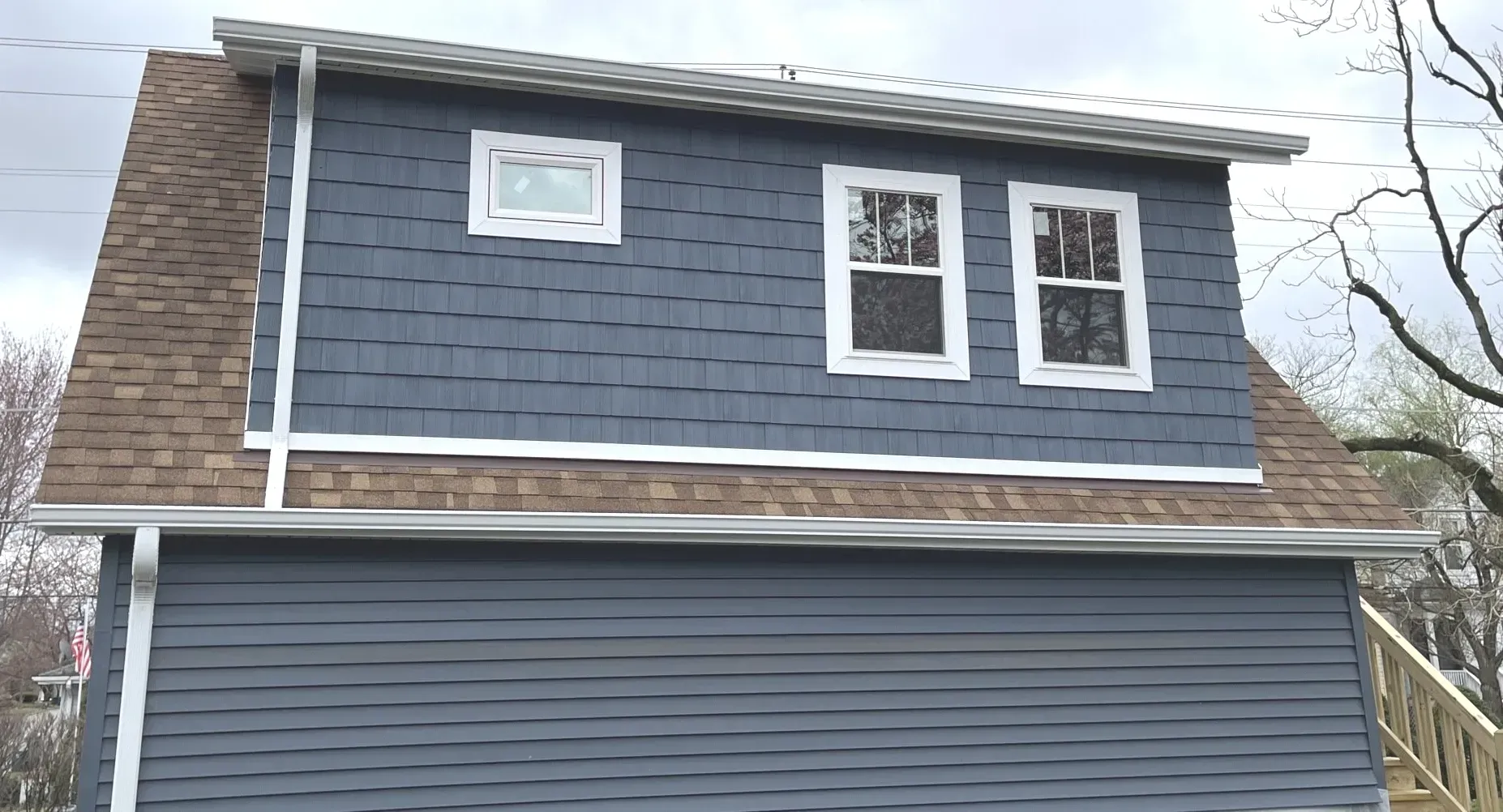A blue house with a brown roof and two windows.